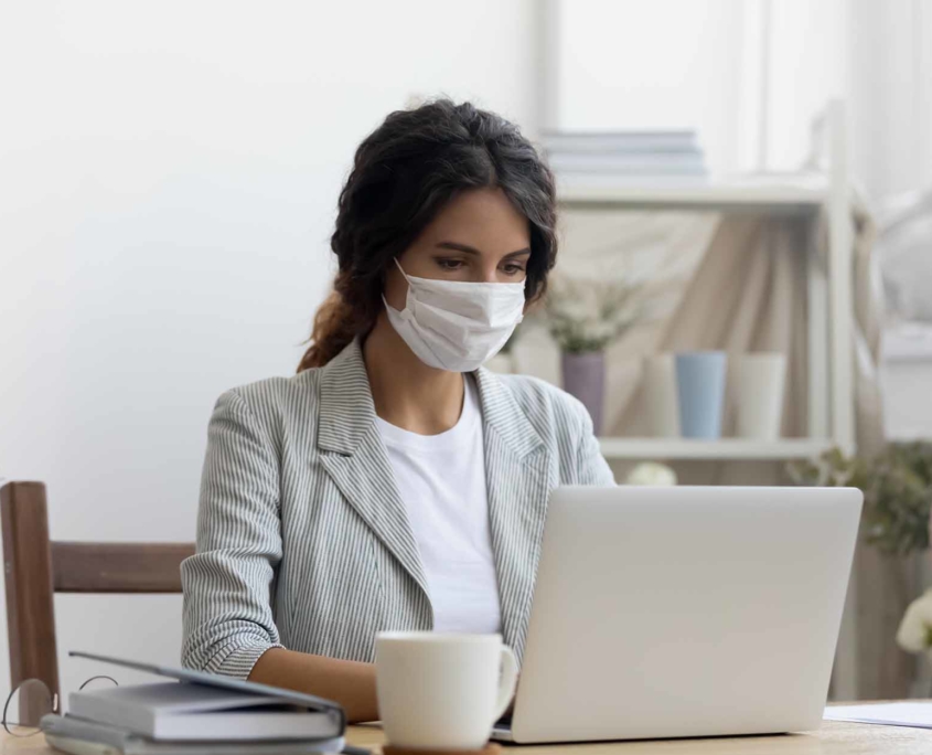Lady wearing a mask working on a laptop